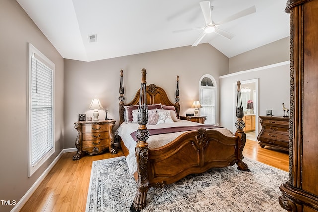 bedroom featuring visible vents, baseboards, ensuite bath, light wood-style flooring, and vaulted ceiling