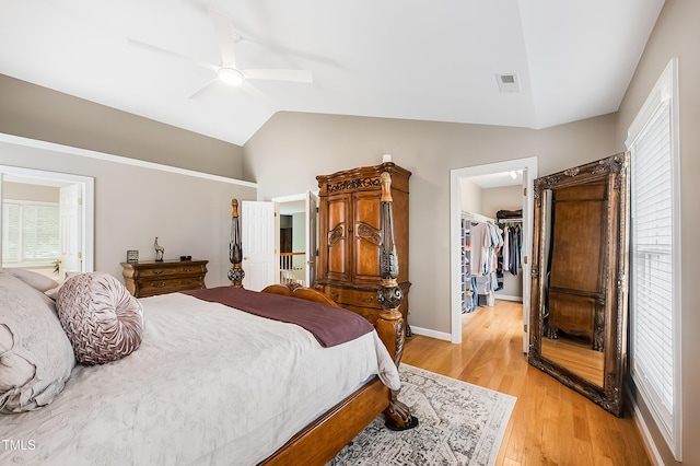 bedroom with visible vents, light wood-style floors, vaulted ceiling, a closet, and a walk in closet