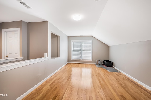 bonus room with baseboards, lofted ceiling, visible vents, and light wood-style floors