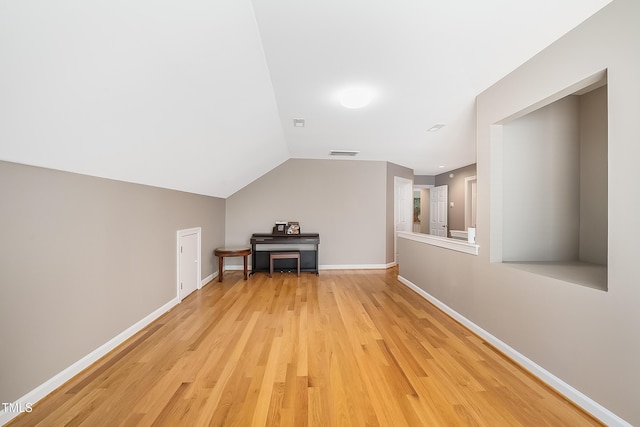 additional living space with vaulted ceiling, light wood-type flooring, visible vents, and baseboards