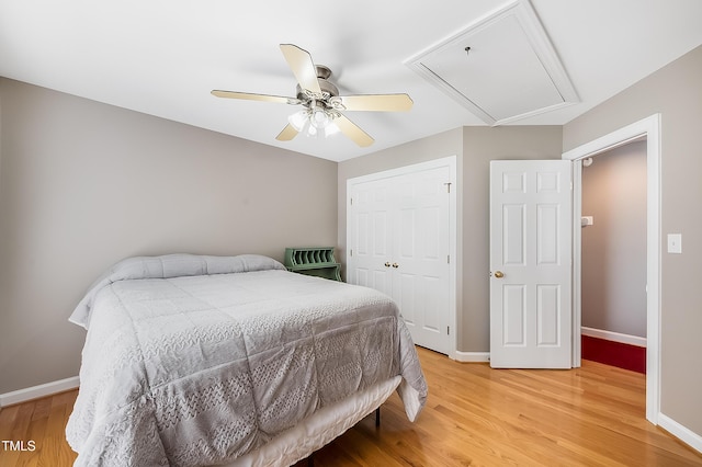 bedroom with ceiling fan, baseboards, light wood-style floors, a closet, and attic access