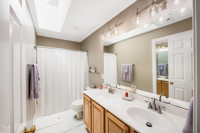 bathroom featuring toilet, a skylight, double vanity, and a sink