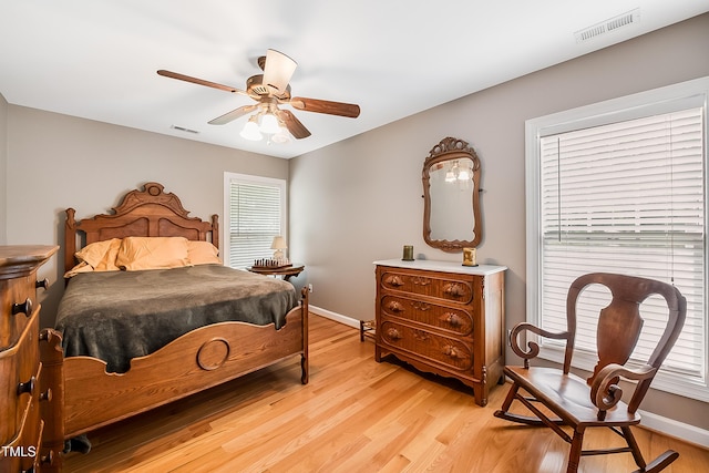 bedroom with light wood finished floors, visible vents, and baseboards