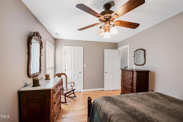 bedroom with light wood finished floors, baseboards, visible vents, and a ceiling fan