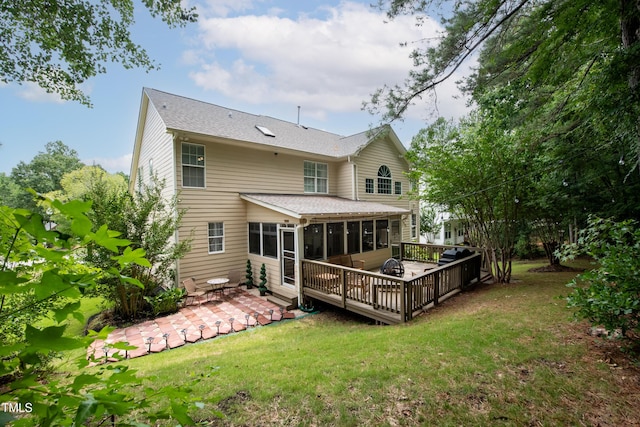 back of property featuring a sunroom, roof with shingles, a deck, a yard, and a patio area