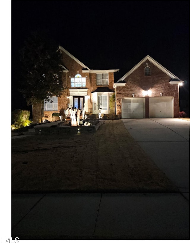 view of front of property with driveway, brick siding, an attached garage, and french doors