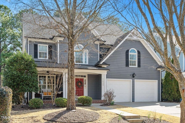 traditional home with roof with shingles, covered porch, concrete driveway, and an attached garage