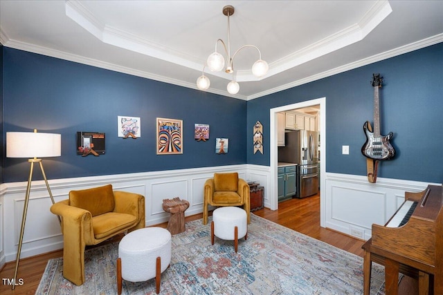 living area featuring a wainscoted wall, a raised ceiling, and wood finished floors