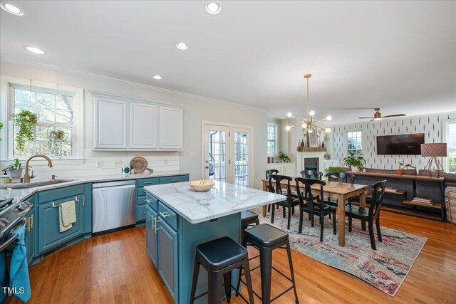 kitchen with open floor plan, appliances with stainless steel finishes, white cabinetry, blue cabinets, and a sink