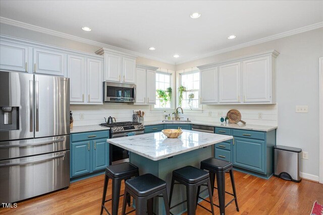 kitchen featuring blue cabinets, light wood-style floors, appliances with stainless steel finishes, and a breakfast bar area