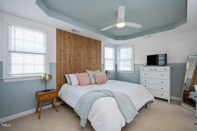 bedroom featuring visible vents, light colored carpet, and a raised ceiling