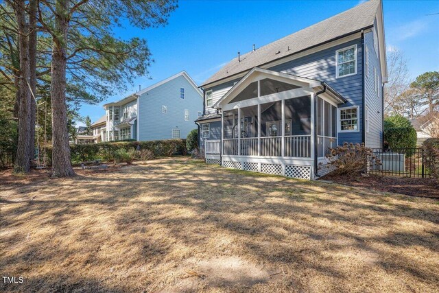 back of house with fence, a lawn, and a sunroom