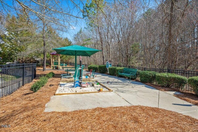 view of patio featuring playground community and fence