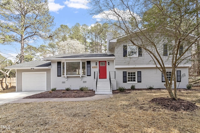 split level home featuring a garage, brick siding, driveway, and fence