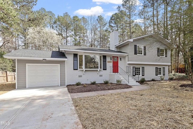 tri-level home featuring a garage, brick siding, driveway, and fence