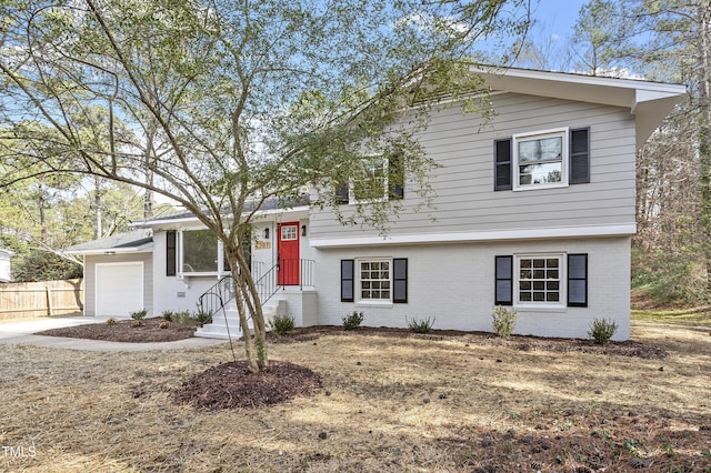 split level home with a garage, fence, and brick siding