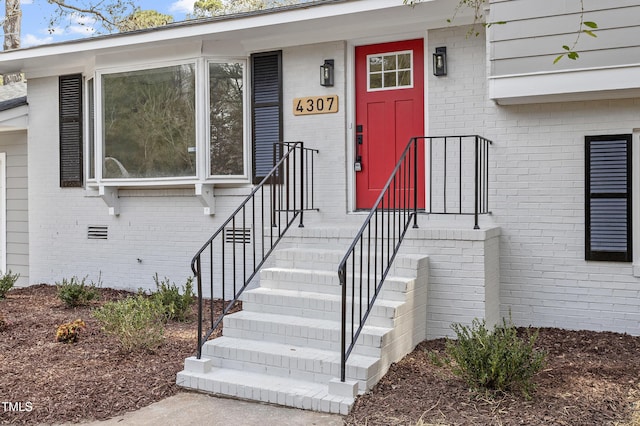 doorway to property with crawl space and brick siding