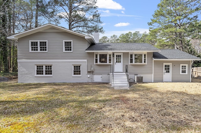 view of front of property with central air condition unit, a chimney, a front lawn, and a shingled roof