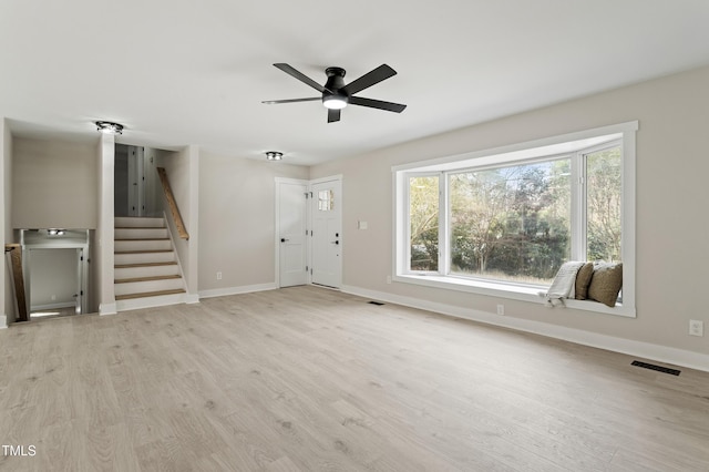 unfurnished living room with visible vents, baseboards, wood finished floors, and stairs