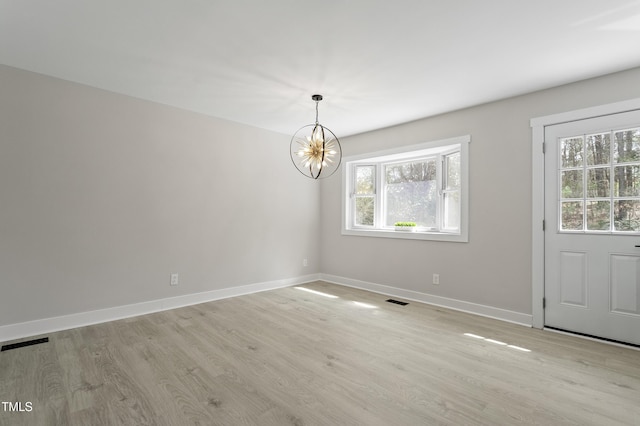 unfurnished dining area with a notable chandelier, light wood-style floors, visible vents, and baseboards