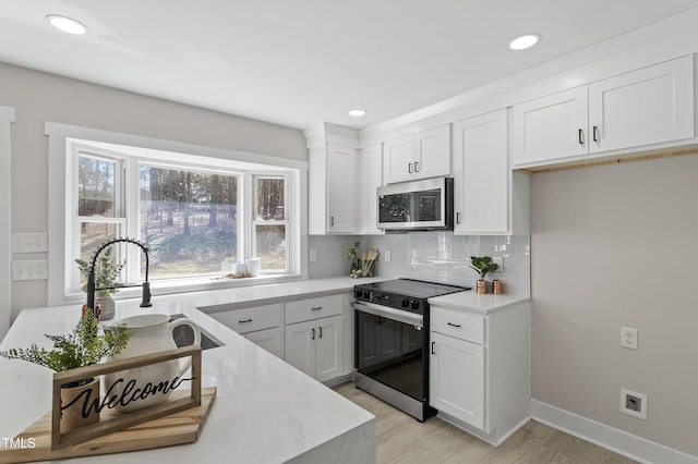 kitchen with stainless steel microwave, tasteful backsplash, light countertops, and electric stove