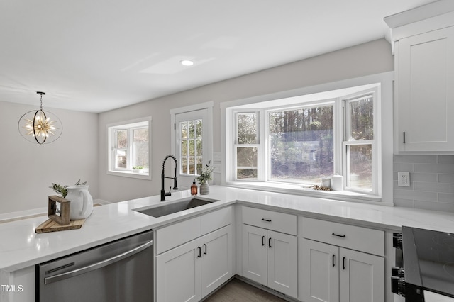 kitchen featuring a sink, backsplash, stainless steel dishwasher, light countertops, and hanging light fixtures