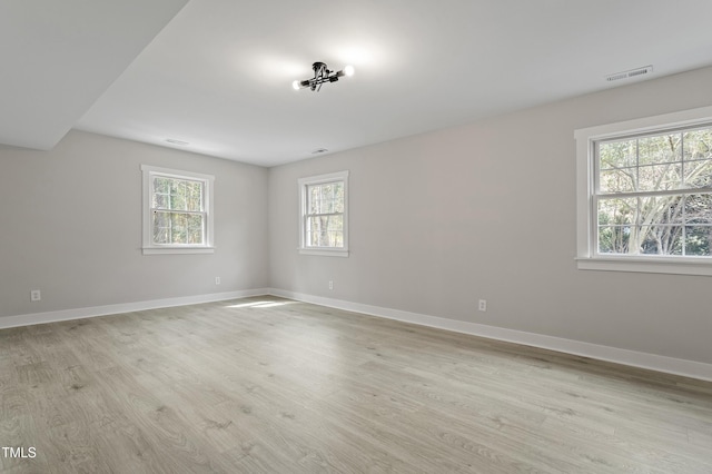 spare room featuring visible vents, baseboards, and light wood finished floors