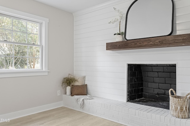 room details with a brick fireplace, wooden walls, wood finished floors, and baseboards