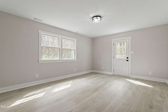 unfurnished room featuring visible vents, light wood-style flooring, and baseboards