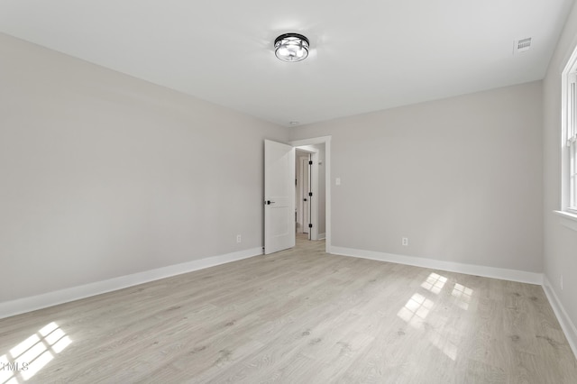 spare room featuring baseboards, visible vents, and light wood finished floors