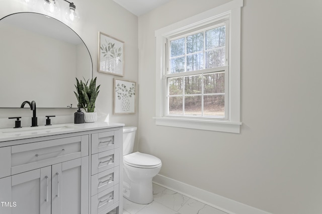 bathroom with marble finish floor, toilet, vanity, and baseboards