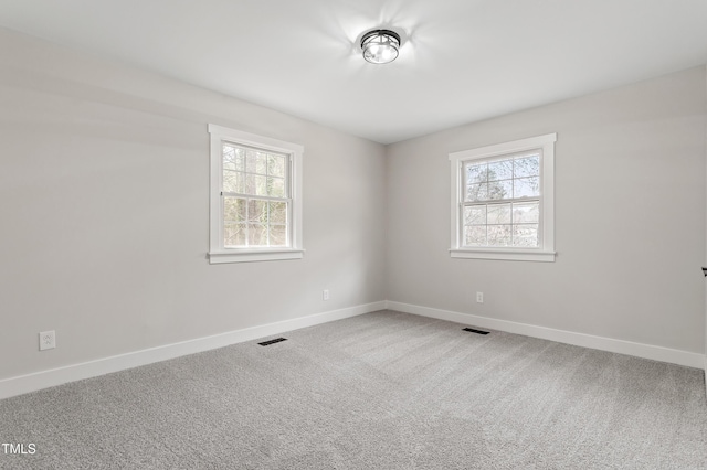 carpeted spare room with visible vents, plenty of natural light, and baseboards