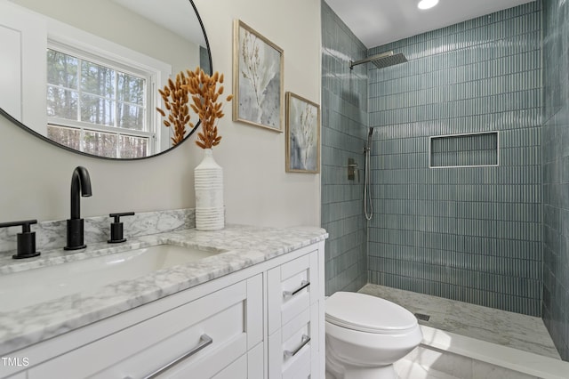 full bathroom featuring vanity, toilet, and a tile shower