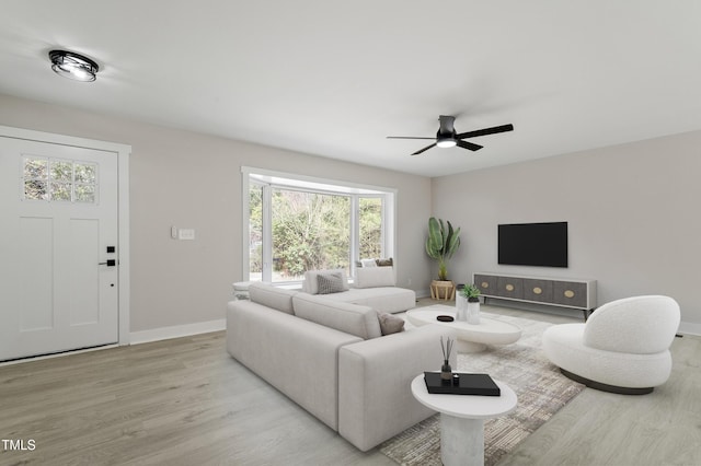 living area featuring light wood-style floors, baseboards, and ceiling fan