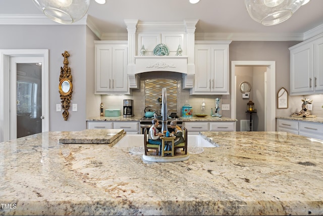 5204 Sandbridge Rd, Bailey, NC 27807 - kitchen featuring light stone countertops, tasteful backsplash, white cabinetry, ornamental molding, and hanging light fixtures