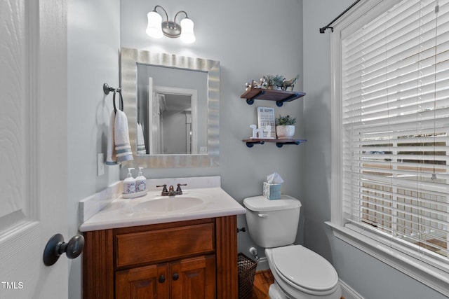 bathroom featuring toilet, baseboards, and vanity