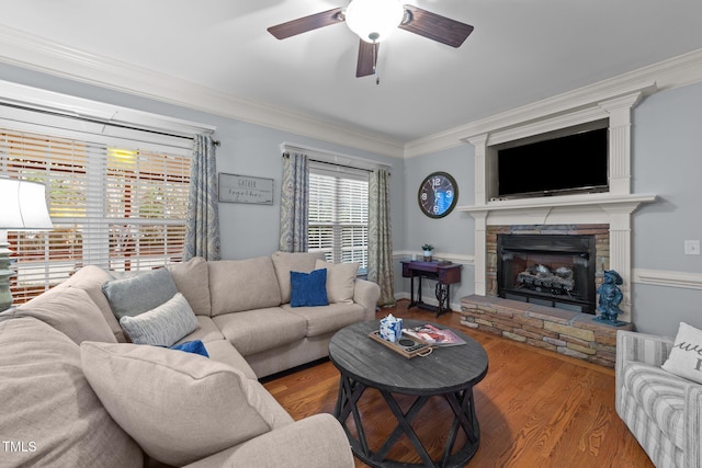 living area featuring ornamental molding, a ceiling fan, a fireplace, and wood finished floors