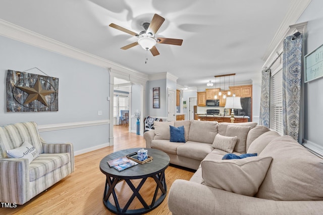 living room featuring baseboards, light wood-style floors, and crown molding