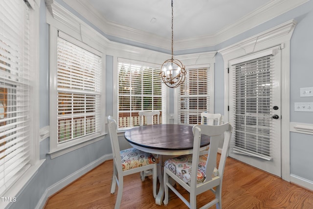 dining space with ornamental molding, a notable chandelier, baseboards, and wood finished floors