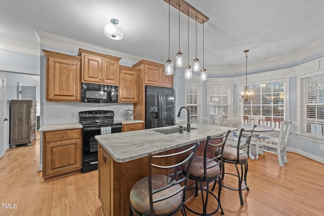 kitchen featuring black appliances, light wood-style flooring, decorative backsplash, and a sink