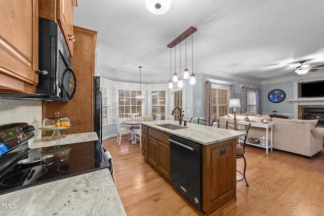 kitchen featuring a breakfast bar, a sink, open floor plan, brown cabinets, and black appliances