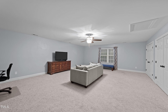 carpeted living room with attic access, baseboards, and ceiling fan