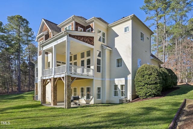 back of property with a yard, a balcony, ceiling fan, and a patio area