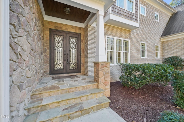 property entrance featuring french doors, stone siding, and brick siding