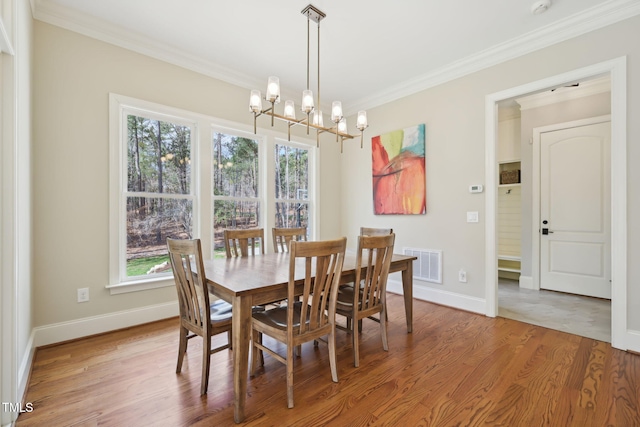 dining space featuring visible vents, light wood-style floors, crown molding, baseboards, and a chandelier