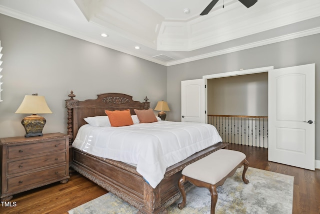 bedroom with recessed lighting, crown molding, a raised ceiling, and wood finished floors