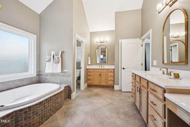 full bath featuring a bath, toilet, two vanities, and a sink