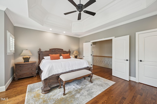 bedroom with a tray ceiling, wood finished floors, baseboards, and ornamental molding