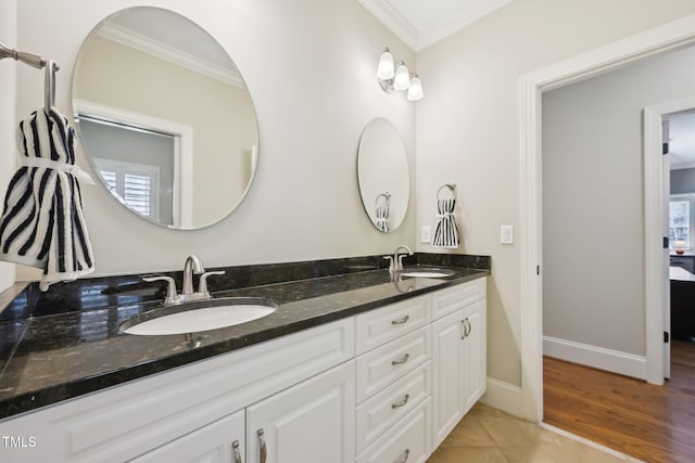 bathroom featuring a sink, baseboards, ornamental molding, and double vanity