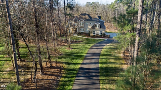 exterior space featuring a wooded view and a front lawn